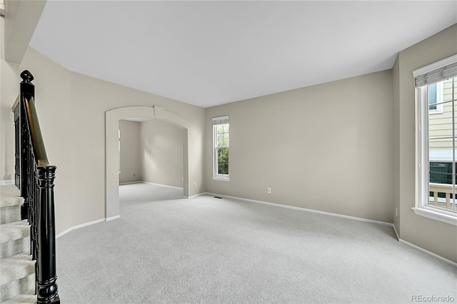 2316 Weatherstone Cir, Highlands Ranch, CO 80126 - unfurnished living room featuring light carpet, arched walkways, and stairway