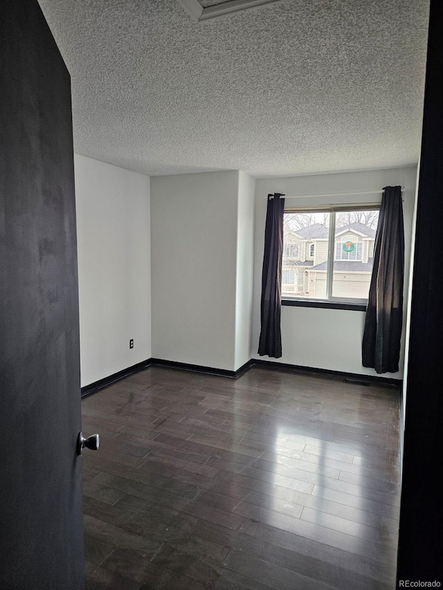 spare room featuring dark hardwood / wood-style flooring and a textured ceiling