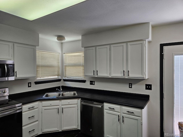 kitchen with appliances with stainless steel finishes, white cabinets, and sink