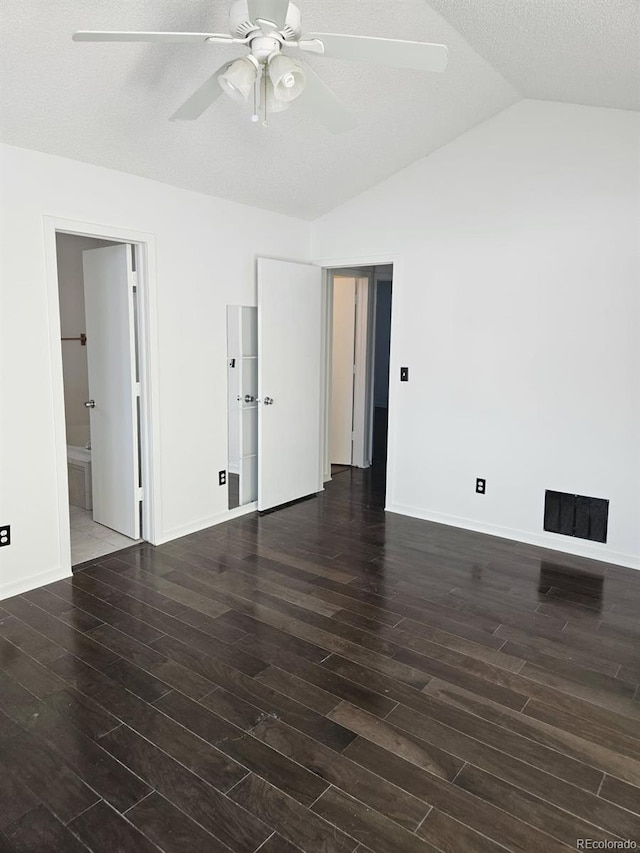 spare room with dark wood finished floors, visible vents, a ceiling fan, vaulted ceiling, and a textured ceiling