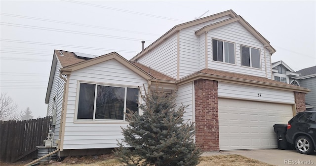 view of front of property featuring a garage, concrete driveway, fence, roof mounted solar panels, and brick siding