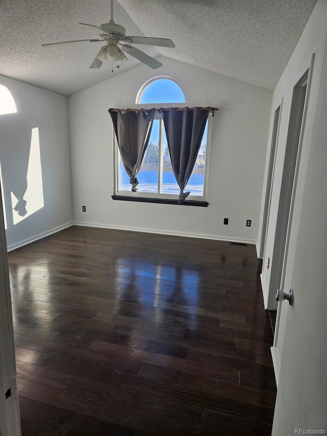 spare room with lofted ceiling, dark wood finished floors, and a textured ceiling