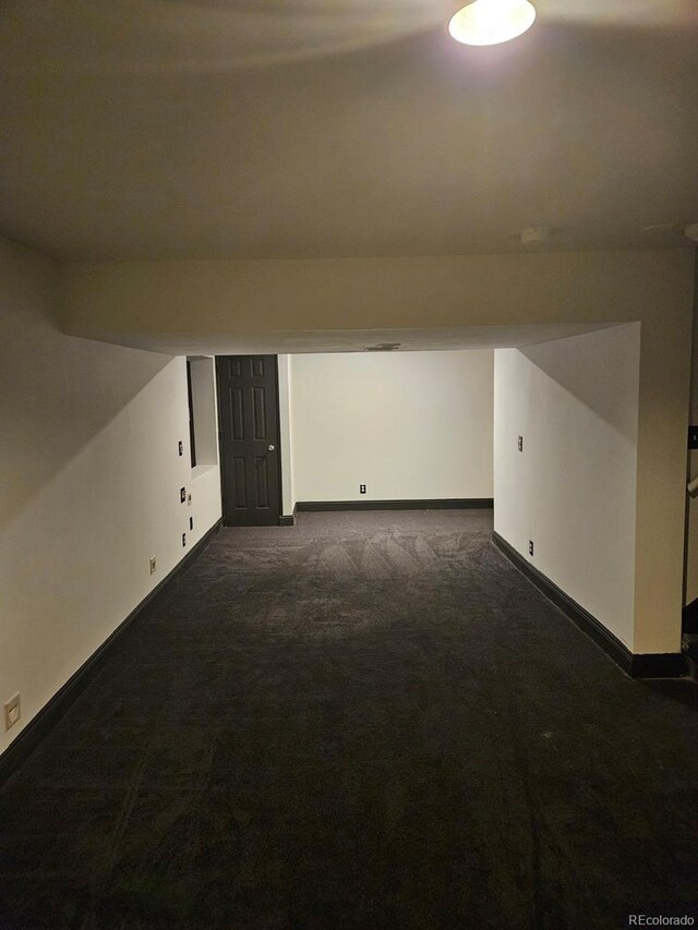 additional living space featuring dark carpet and baseboards