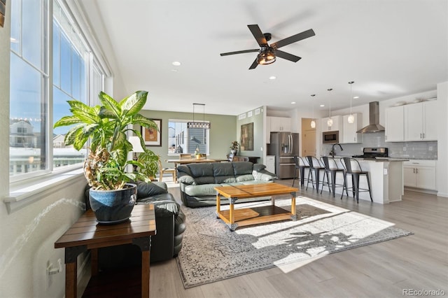 living area with recessed lighting, light wood-style floors, and ceiling fan