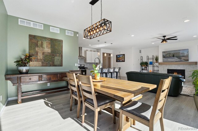 dining space featuring visible vents, a lit fireplace, and wood finished floors