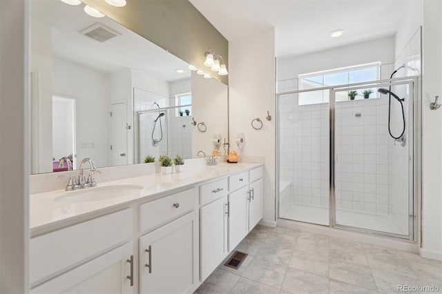 full bath featuring a sink, visible vents, double vanity, and a shower stall