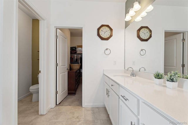 full bathroom featuring tile patterned flooring, a walk in closet, baseboards, toilet, and vanity