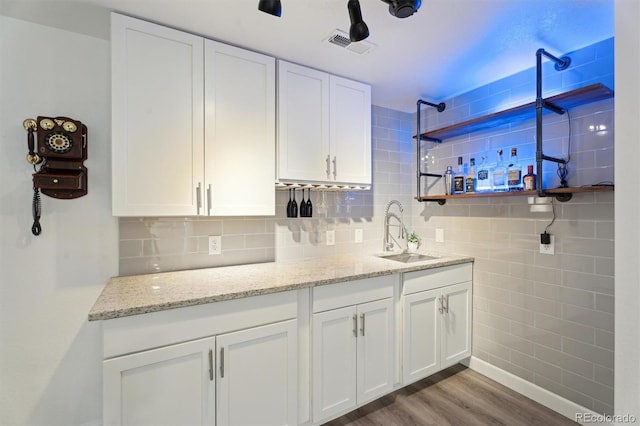 interior space with tasteful backsplash, wood finished floors, visible vents, and a sink