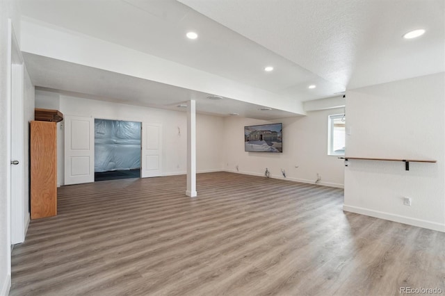 basement featuring recessed lighting, baseboards, and light wood-style floors