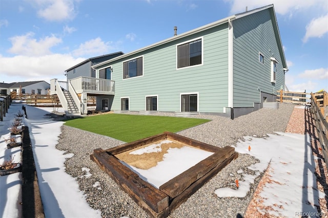 rear view of house featuring a deck, stairway, a lawn, and fence