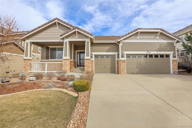 craftsman-style house featuring covered porch, an attached garage, a tile roof, and concrete driveway