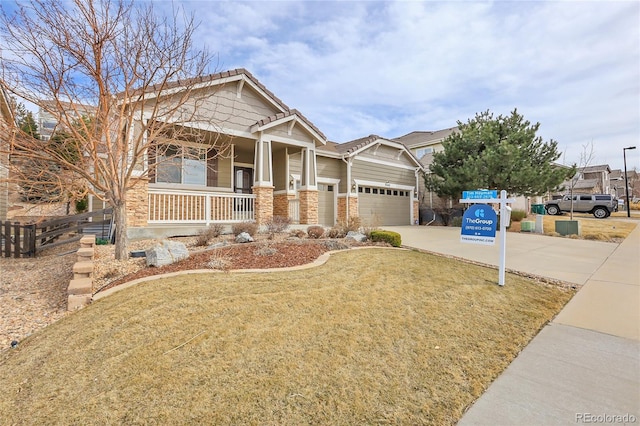 craftsman house featuring an attached garage, a front yard, covered porch, and driveway