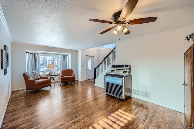 living room featuring crown molding, ceiling fan, wood-type flooring, and a textured ceiling