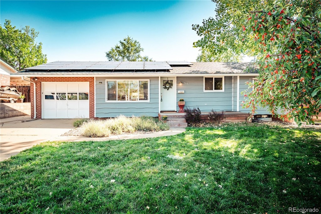 ranch-style home with a front yard, a garage, and solar panels