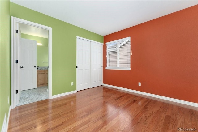 1241 S Akron Way, Denver, CO 80247 - unfurnished bedroom featuring light wood finished floors, baseboards, a closet, and ensuite bath