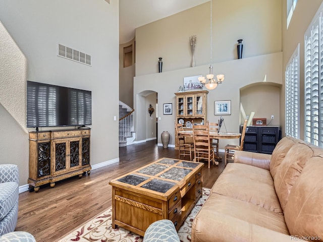 11074 Grayledge Cir, Highlands Ranch, CO 80130 - living room with arched walkways, a high ceiling, stairway, wood finished floors, and a chandelier