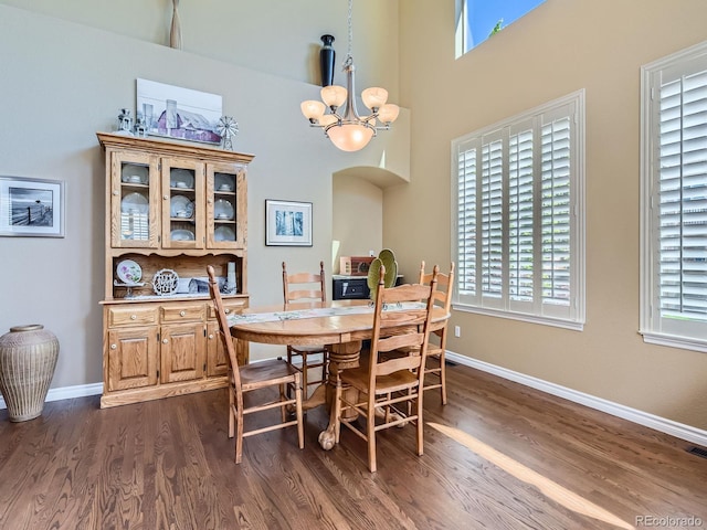 11074 Grayledge Cir, Highlands Ranch, CO 80130 - dining room featuring arched walkways, a chandelier, dark wood finished floors, healthy amount of natural light, and a towering ceiling