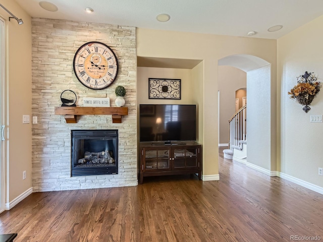 11074 Grayledge Cir, Highlands Ranch, CO 80130 - living area featuring wood finished floors, arched walkways, a stone fireplace, and stairs