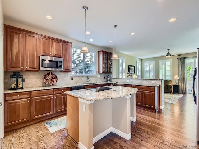 11074 Grayledge Cir, Highlands Ranch, CO 80130 - kitchen featuring a peninsula, black appliances, wood finished floors, tasteful backsplash, and brown cabinets