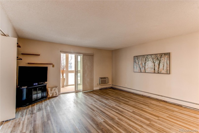 unfurnished living room with a baseboard heating unit, a wall mounted AC, wood finished floors, and a textured ceiling