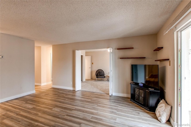 living room with a textured ceiling, baseboards, and wood finished floors