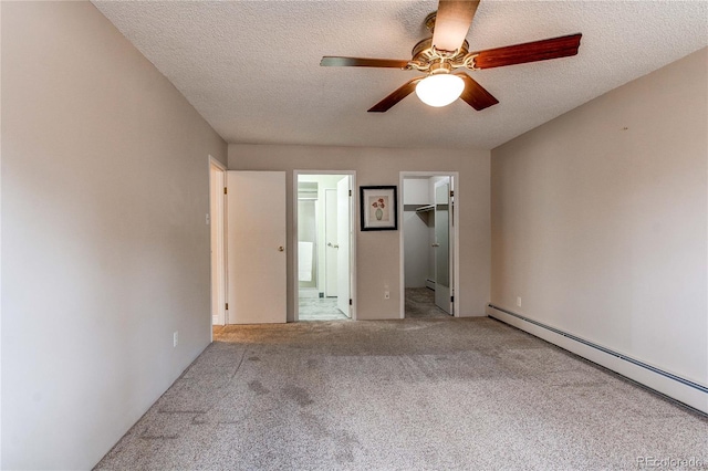 unfurnished bedroom with carpet floors, a baseboard radiator, a closet, a spacious closet, and a textured ceiling