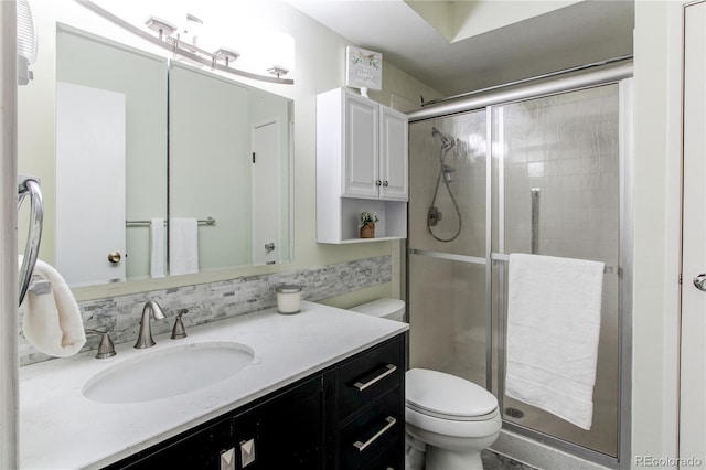 full bath with backsplash, a shower stall, toilet, and vanity