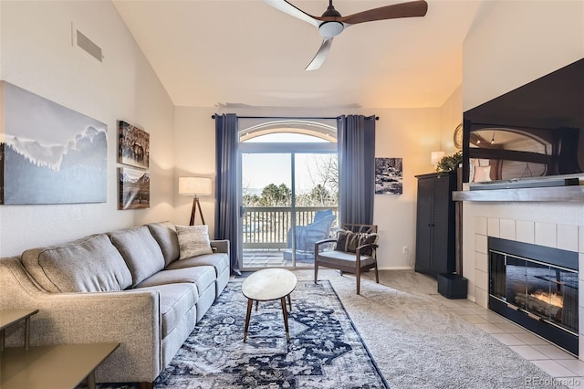 living room featuring a tile fireplace, lofted ceiling, light tile patterned flooring, and ceiling fan