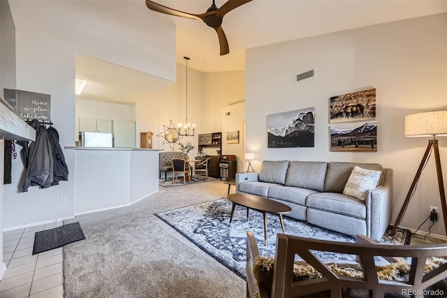 carpeted living room featuring ceiling fan with notable chandelier and high vaulted ceiling