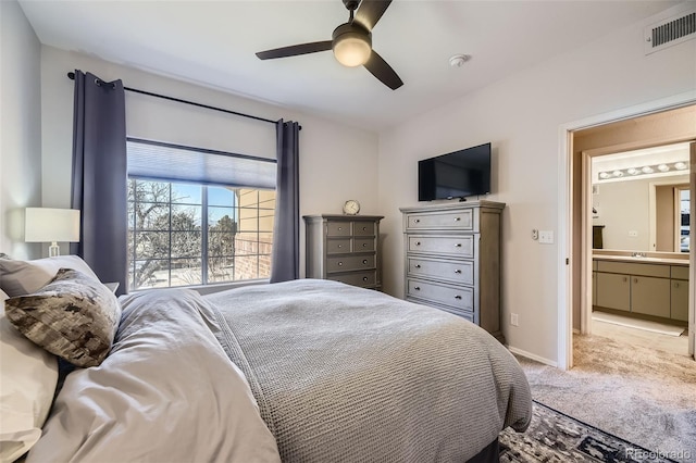 bedroom with light colored carpet, ceiling fan, and ensuite bath