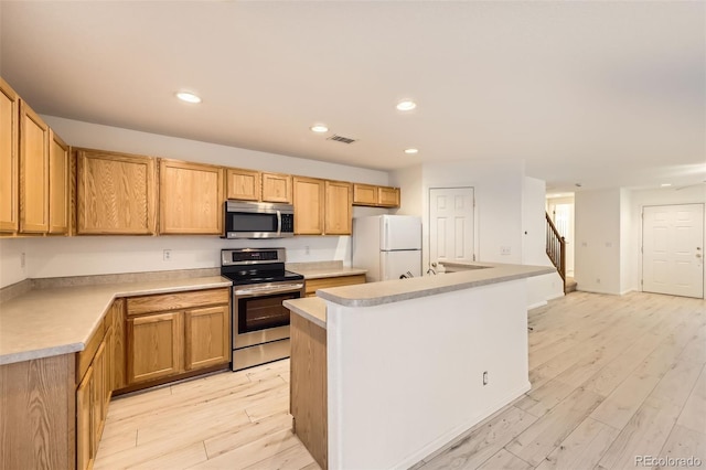 kitchen with light hardwood / wood-style flooring, stainless steel appliances, and a center island