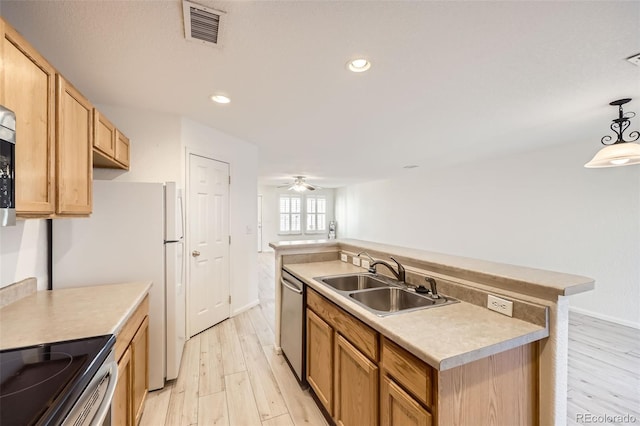 kitchen with appliances with stainless steel finishes, pendant lighting, sink, a kitchen island with sink, and light wood-type flooring