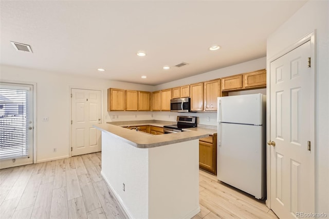 kitchen with light brown cabinets, a kitchen island, light hardwood / wood-style floors, and appliances with stainless steel finishes