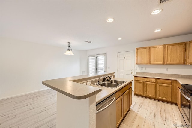 kitchen with sink, decorative light fixtures, light wood-type flooring, an island with sink, and stainless steel appliances