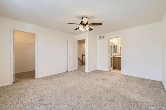 unfurnished bedroom with a spacious closet, light colored carpet, ceiling fan, and a closet