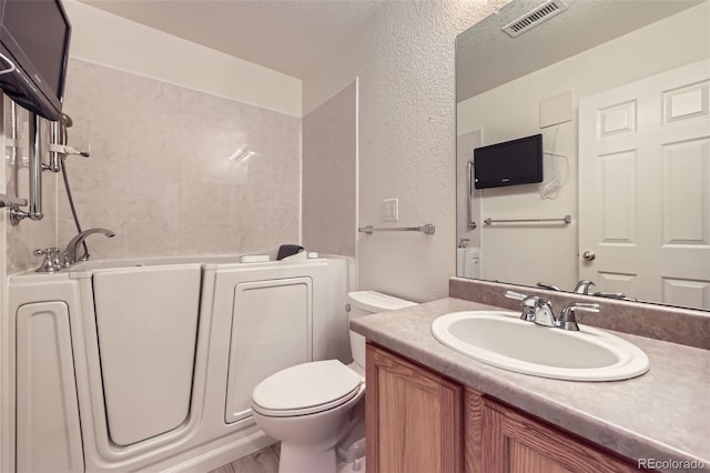 bathroom with vanity, a textured ceiling, a bathtub, and toilet