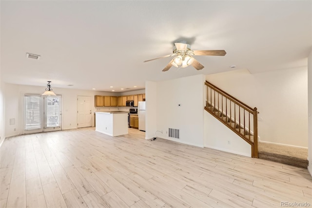 unfurnished living room featuring ceiling fan and light hardwood / wood-style flooring