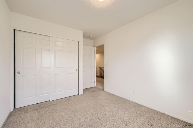 unfurnished bedroom featuring light colored carpet and a closet