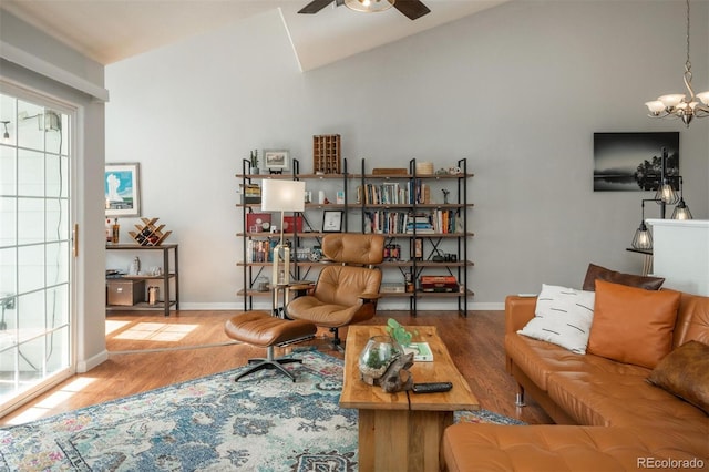 interior space featuring baseboards, ceiling fan with notable chandelier, wood finished floors, and vaulted ceiling