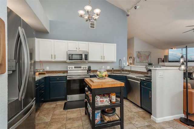 kitchen with track lighting, wooden counters, stainless steel appliances, white cabinetry, and a sink