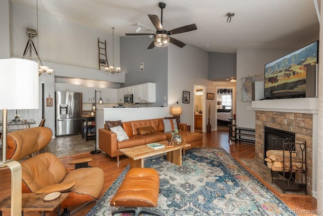 living room with wood finished floors, ceiling fan, a fireplace, and vaulted ceiling