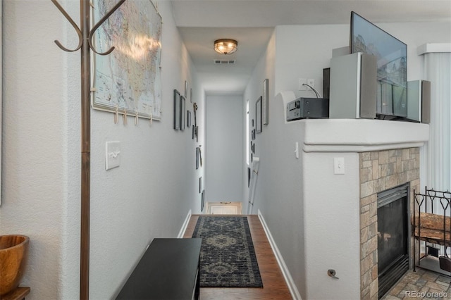 hallway with baseboards, visible vents, and wood finished floors
