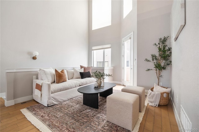 living room featuring a towering ceiling and light hardwood / wood-style floors