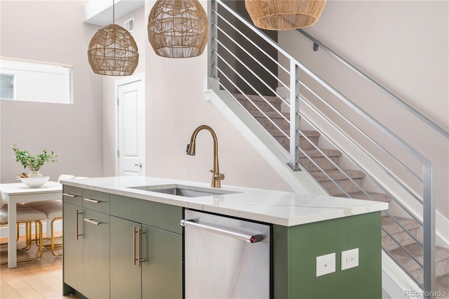 kitchen with sink, stainless steel dishwasher, green cabinets, pendant lighting, and light hardwood / wood-style floors