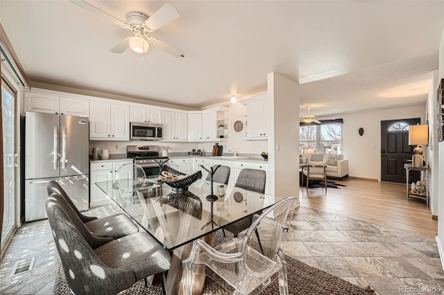 dining room with visible vents, a ceiling fan, baseboards, and light wood-type flooring