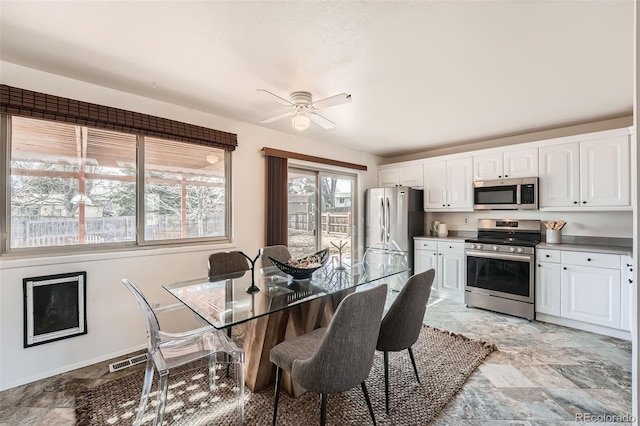 dining space featuring visible vents, stone finish floor, baseboards, and ceiling fan