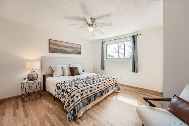 bedroom with ceiling fan, wood finished floors, baseboards, and a textured ceiling