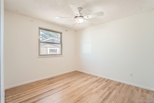 empty room with ceiling fan, wood finished floors, baseboards, and a textured ceiling