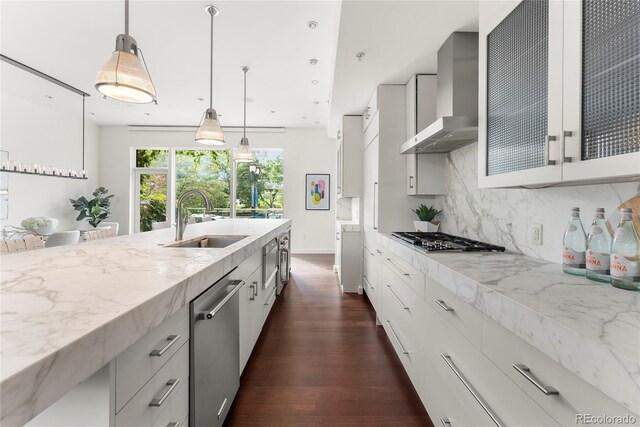 kitchen featuring stainless steel appliances, dark hardwood / wood-style flooring, light stone counters, sink, and wall chimney exhaust hood