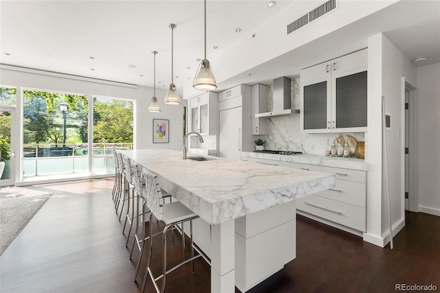 kitchen with visible vents, decorative backsplash, a sink, modern cabinets, and wall chimney exhaust hood